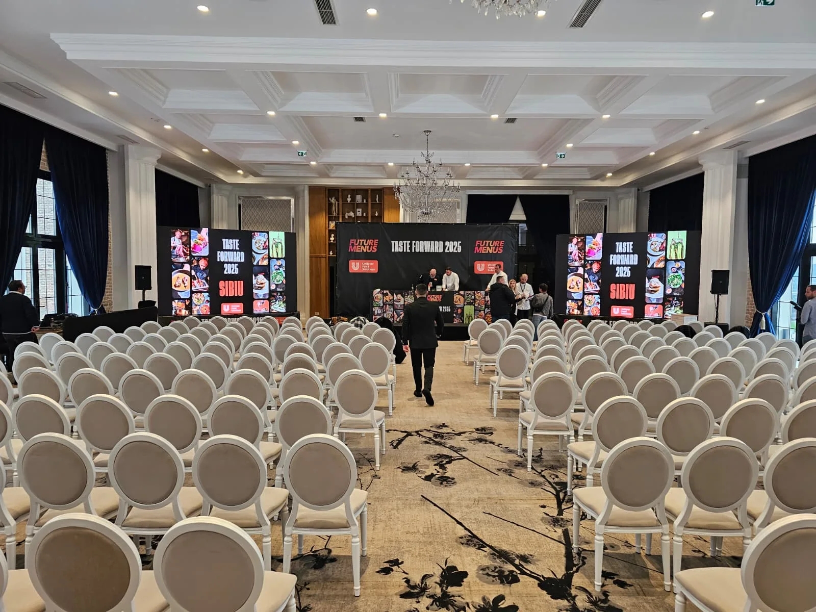 UniChef Cup 2025 conference room in Sibiu with the event stage, twin LED displays and audience seating.