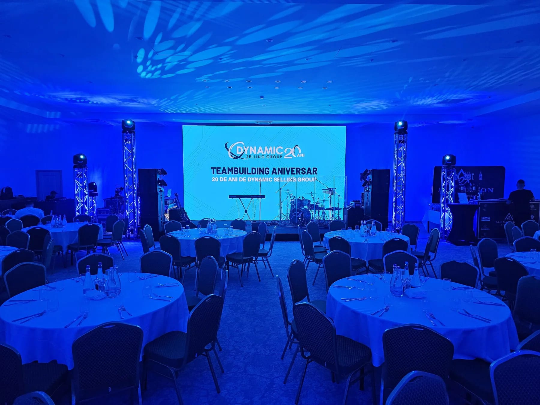 Dynamic Selling Group anniversary event stage in Sinaia with LED screen, blue lighting and banquet seating.