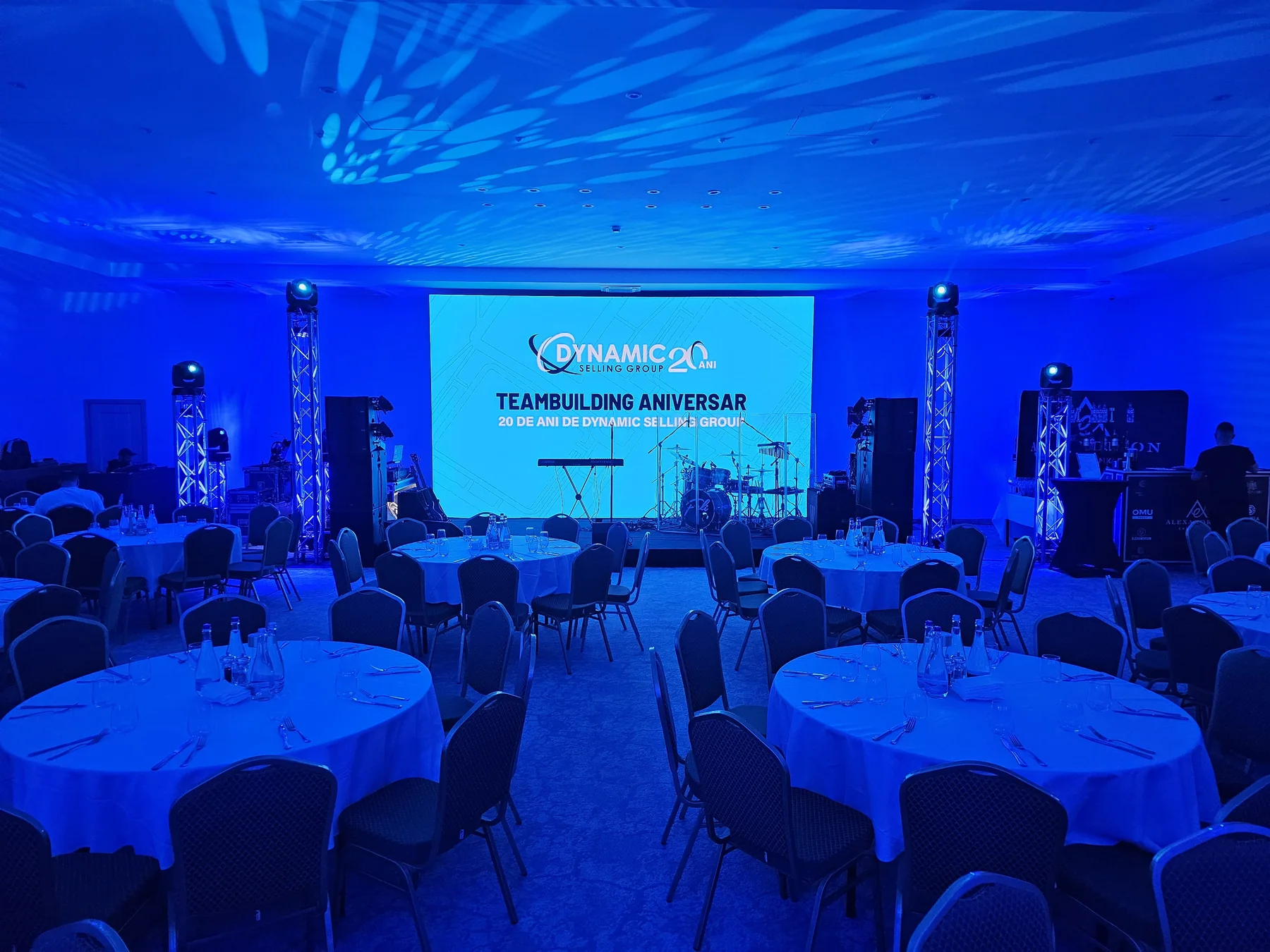 Dynamic Selling Group anniversary event stage in Sinaia with LED screen, blue lighting and banquet seating.