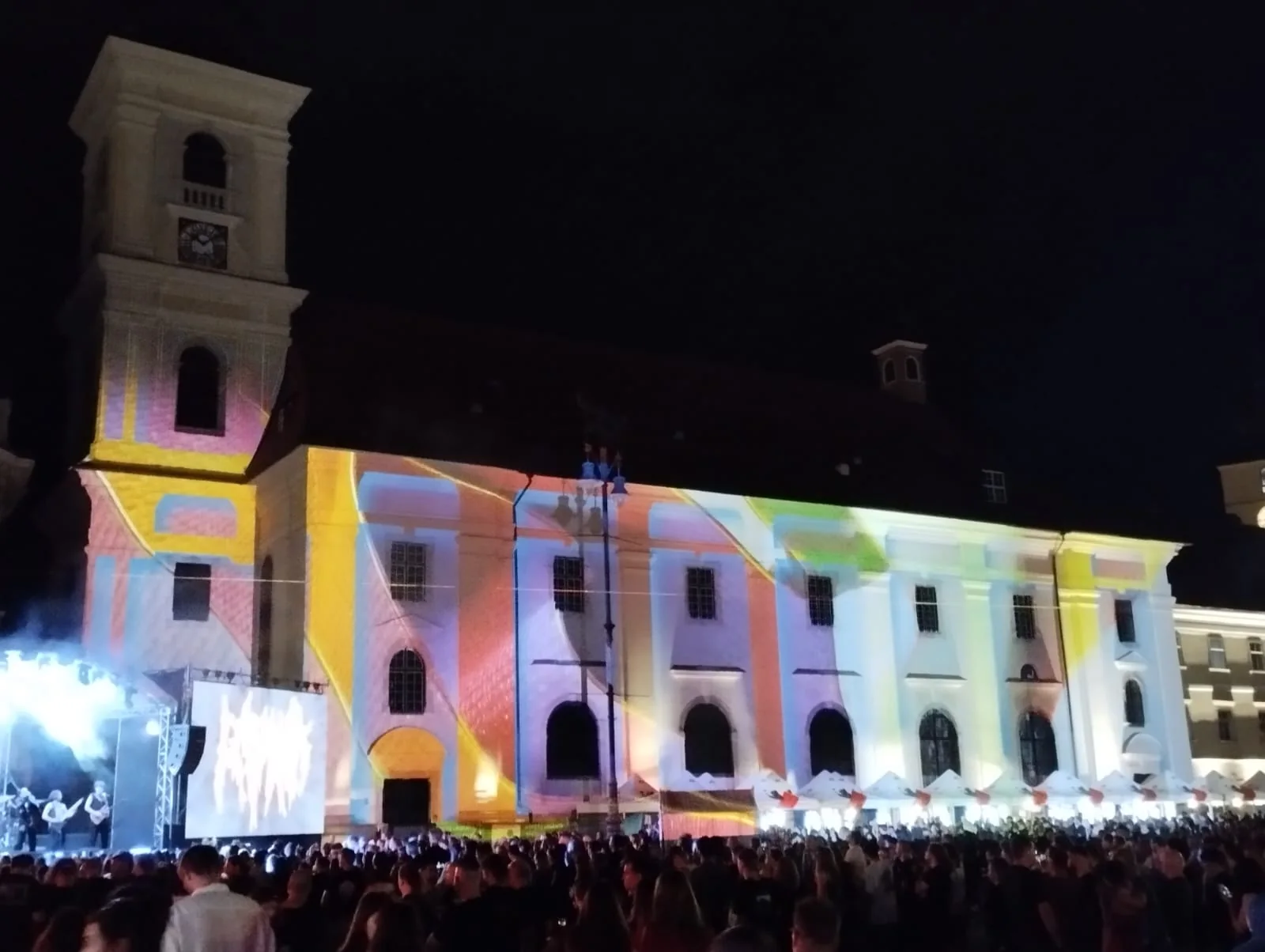 Artmania facade projection in Piața Mare, Sibiu, with colorful content across the building and audience in front.