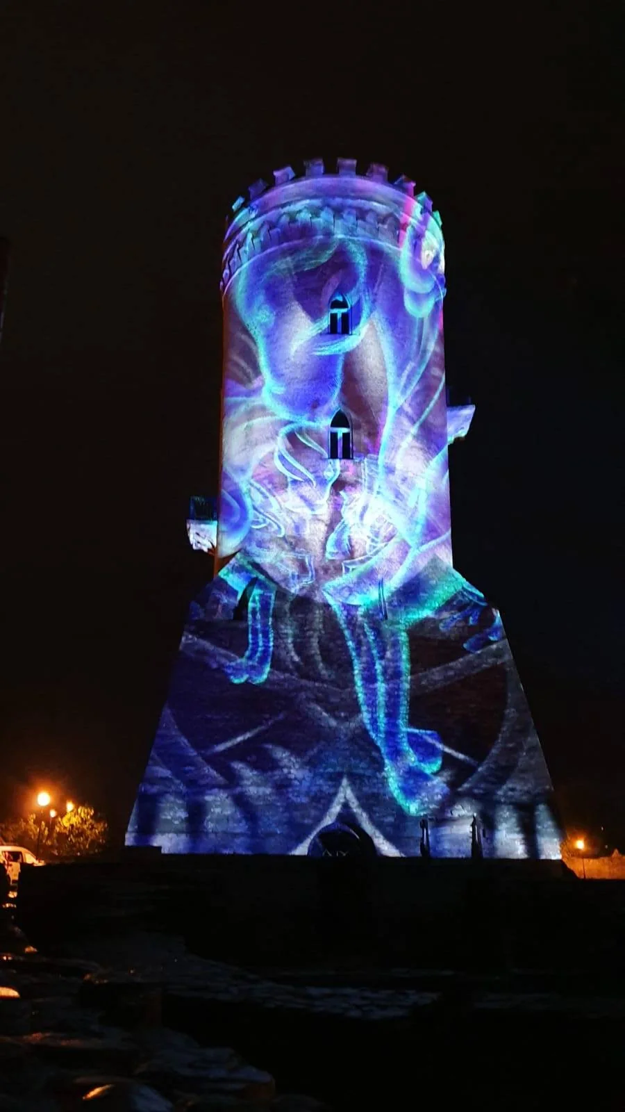 Portrait view of projected visual content covering Turnul Chindiei in Târgoviște at night.