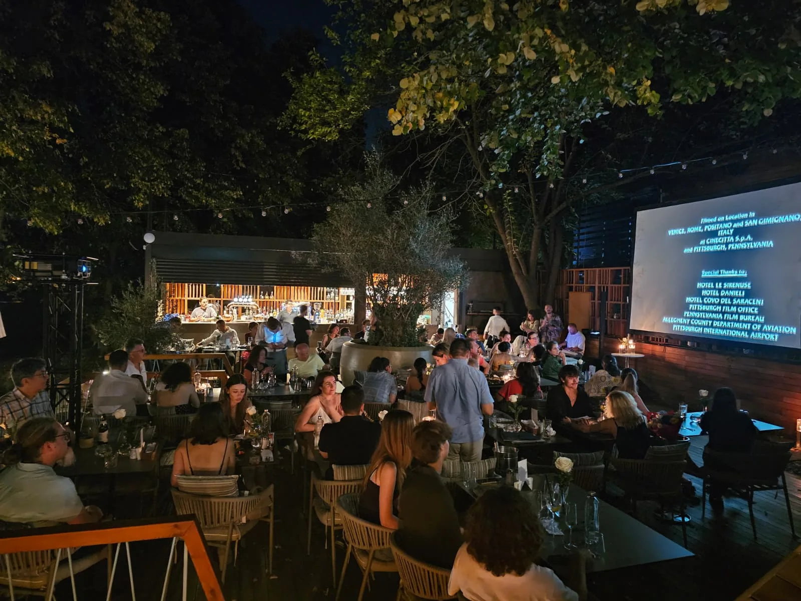 Guests seated around the outdoor projection screen during the Blue Restaurant film event in Bucharest.