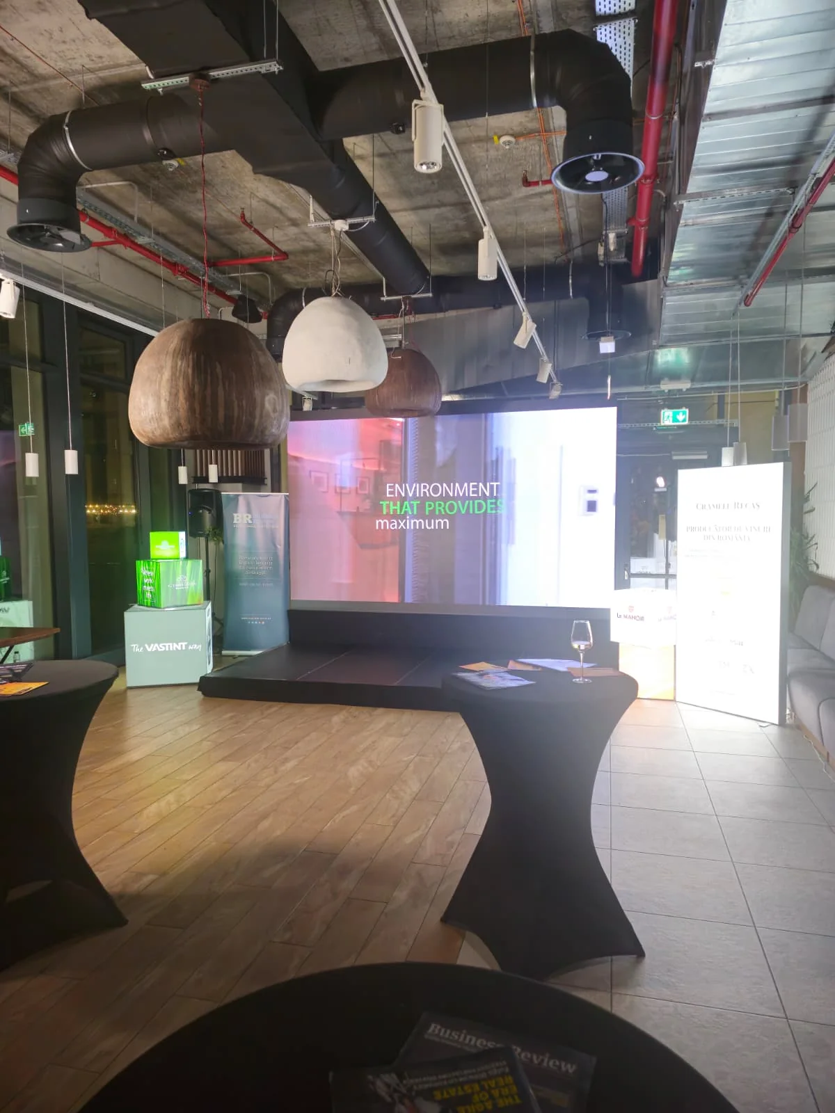 Event screen and cocktail-table setup inside the Spoonfool venue for Business Review in Bucharest.