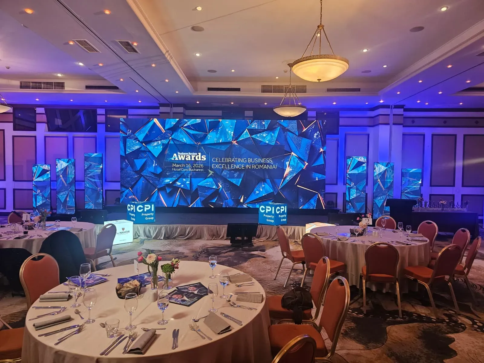 Large LED screen and digital poster displays across the Business Review event stage at Hotel Caro in Bucharest.
