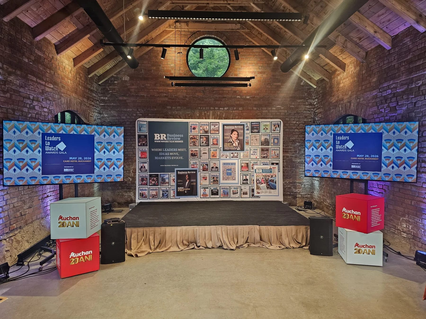 Stage with two professional displays and branded presentation content at Caro Atelier in Bucharest.