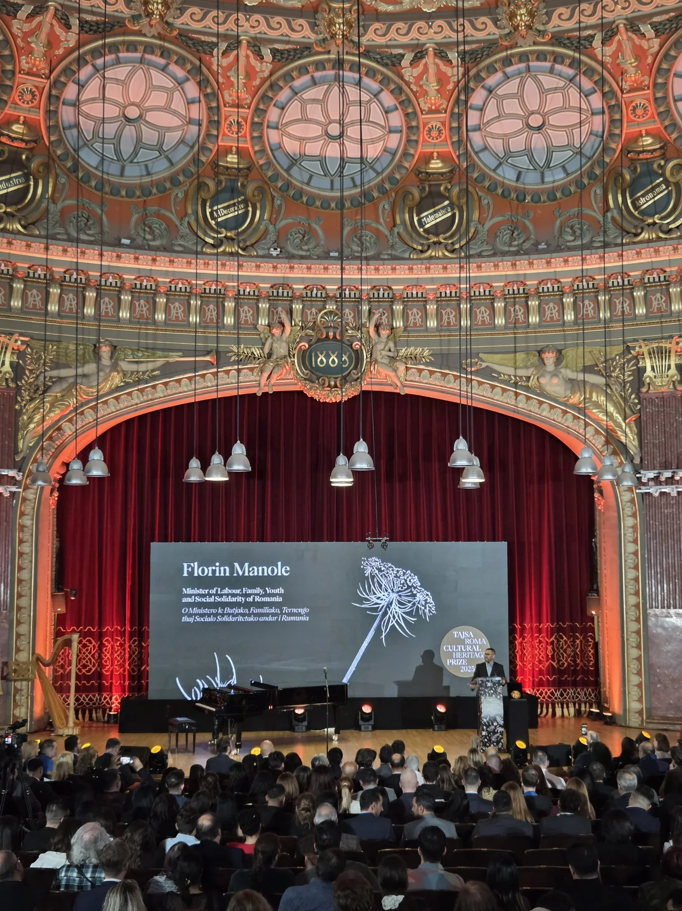 Audience viewing a presentation on stage during the European Roma Institute event at the Romanian Athenaeum.