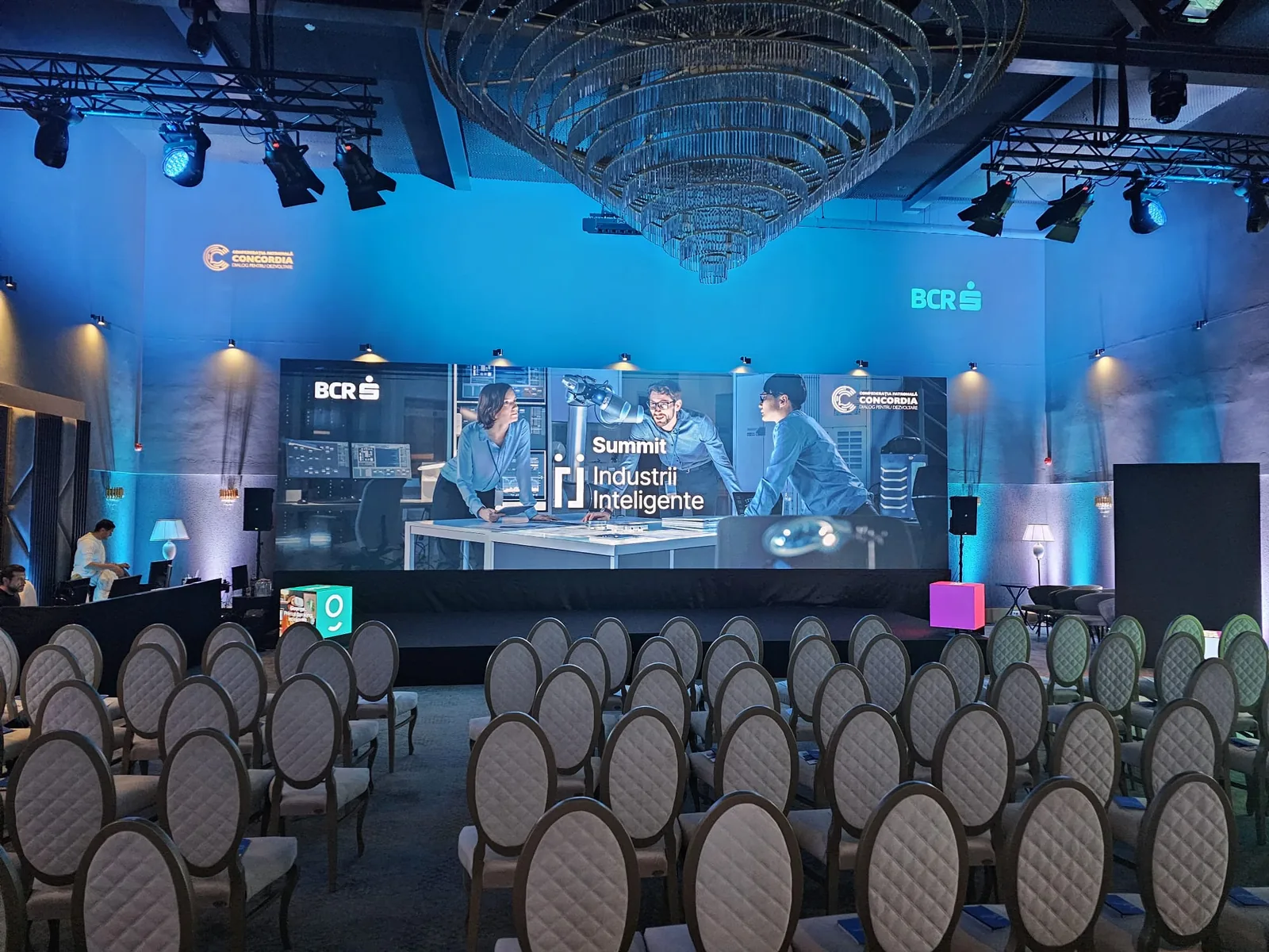 Tigers Summit Romania stage at Nayam with panel seating, presentation screens and blue event lighting in Bucharest.