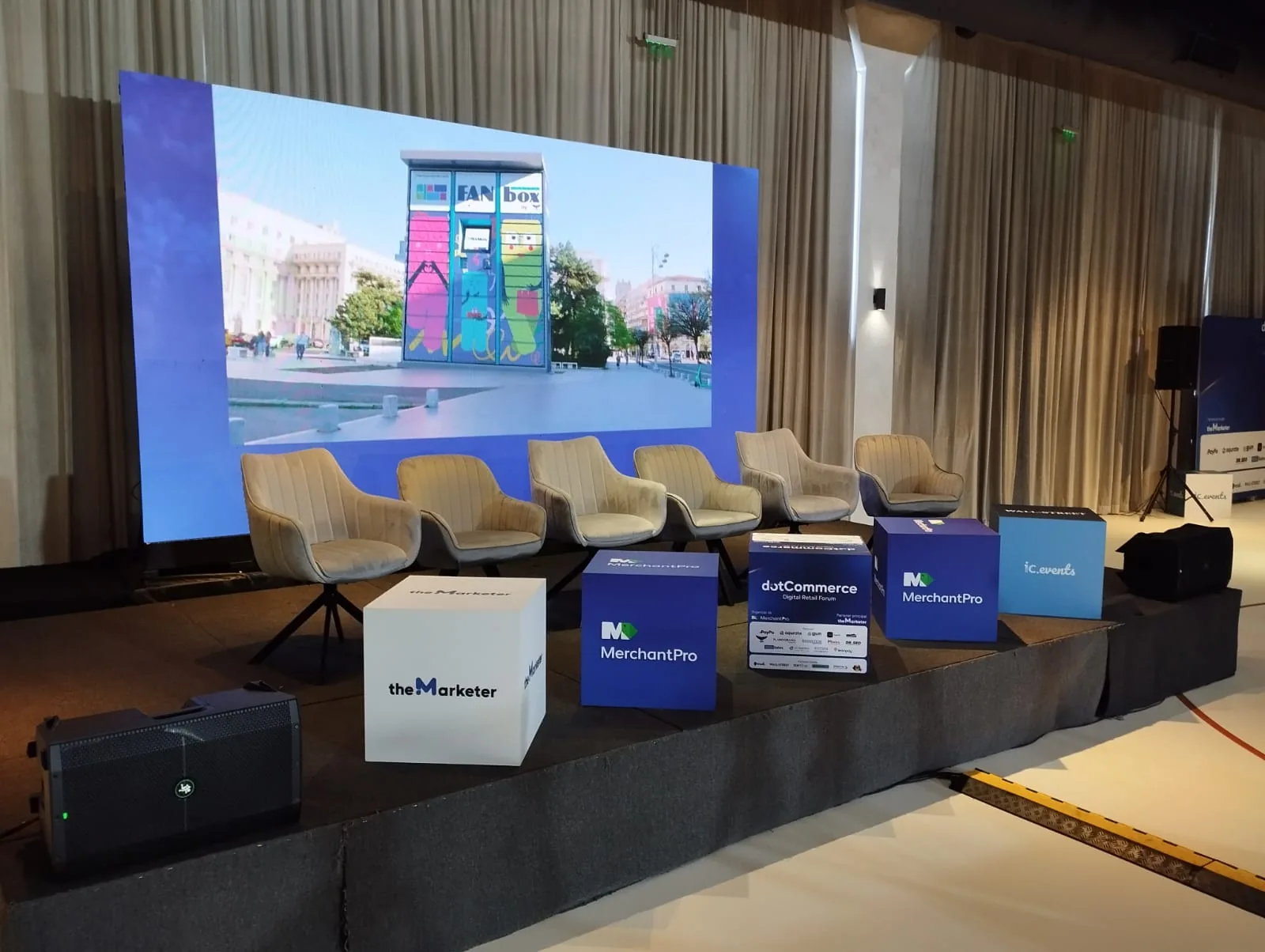 Dot Commerce conference stage at Terra Events Hall with a large presentation display, panel seating and branded event cubes in Bucharest.