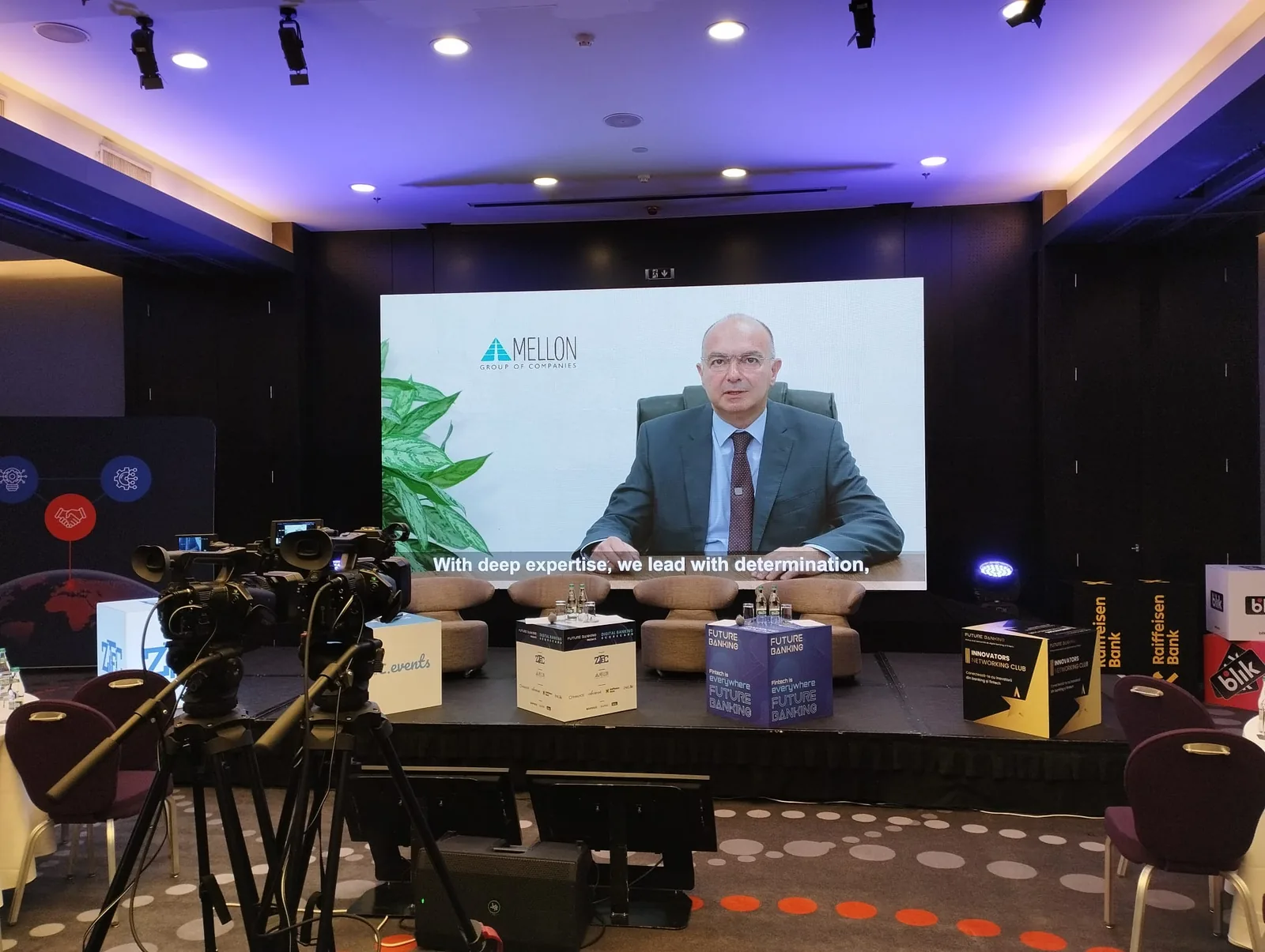 Speaker displayed on the main event screen at the Digital Banking Scorecard conference at Sheraton Bucharest, with camera equipment positioned in front of the stage.