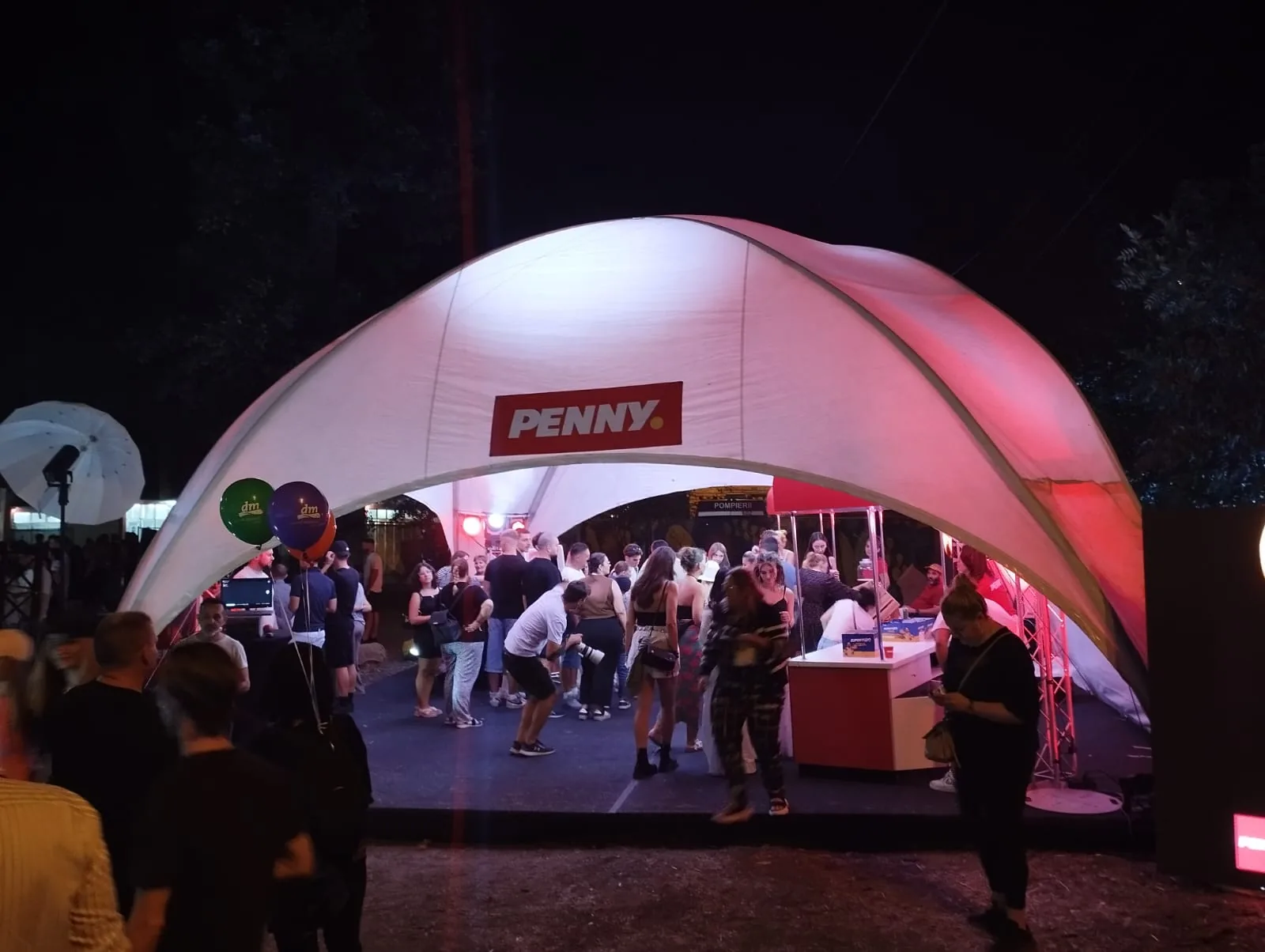 PENNY brand activation at ROCA Festival in Iasi at night with visitors inside the branded event tent.