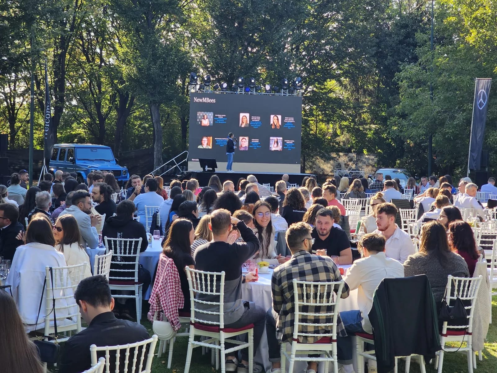 Audience seated outdoors at the Mercedes-Benz event at Crowne Plaza with the LED screen and vehicle display in Bucharest.