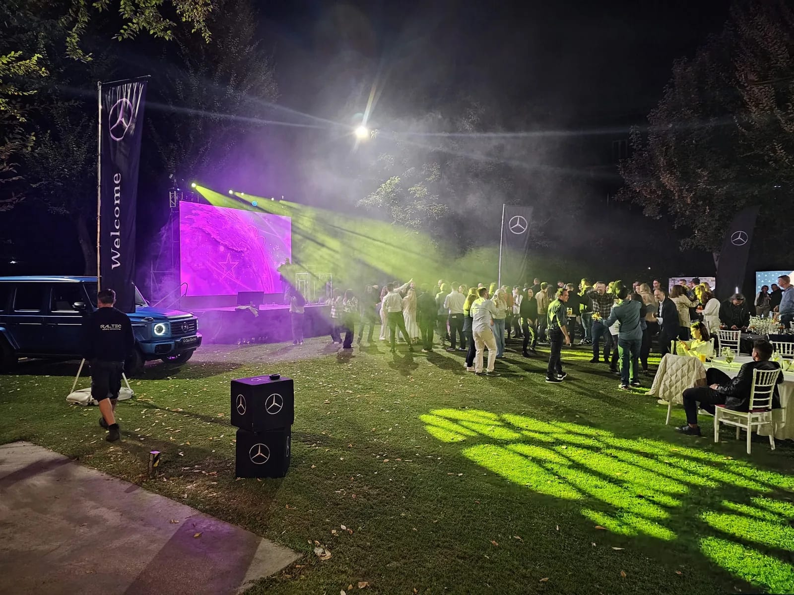Guests at the Mercedes-Benz event at Crowne Plaza with the outdoor LED screen, branded flags and event lighting in Bucharest.