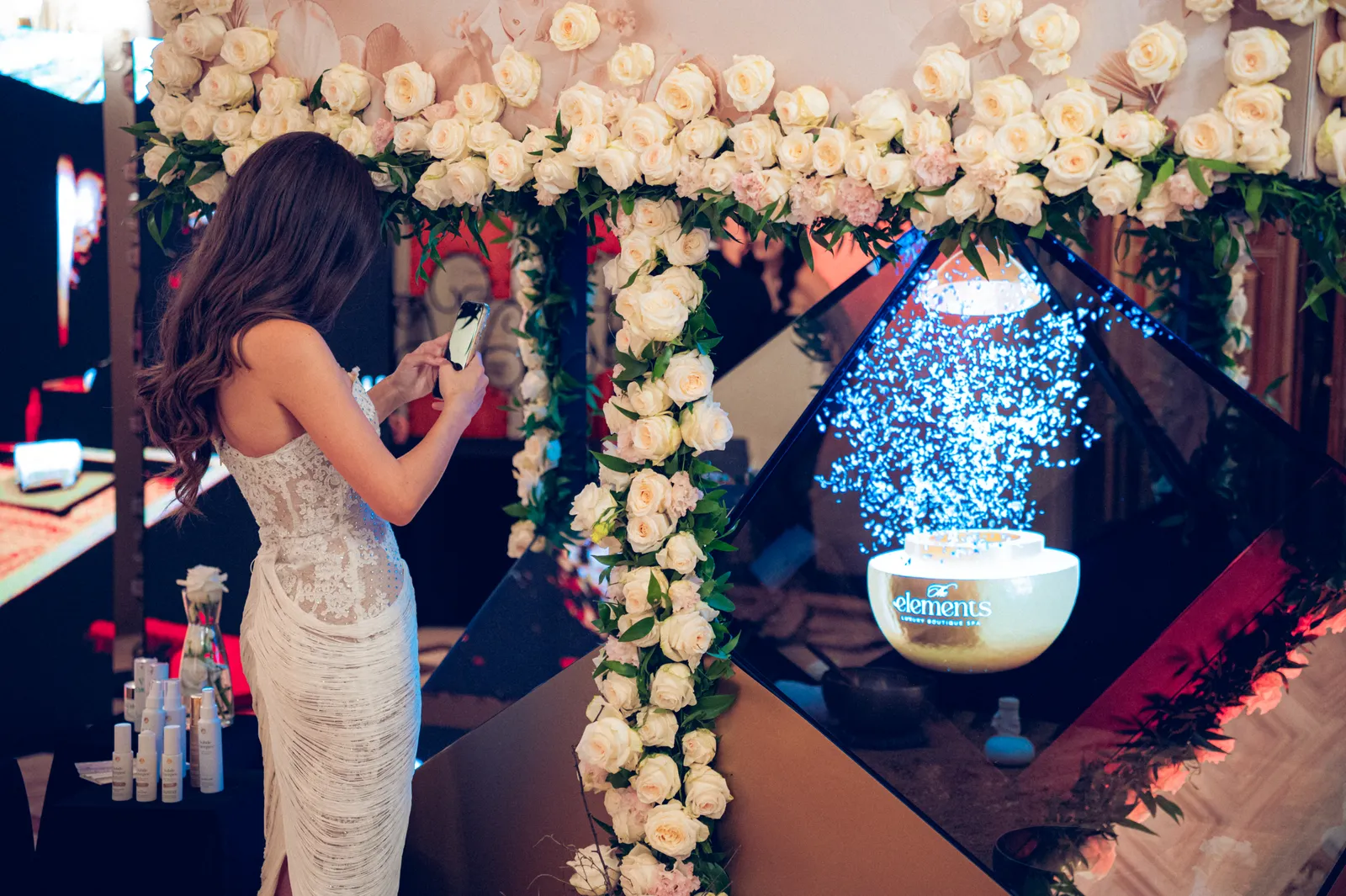 Guest in a white dress filming the golden egg hologram inside the rose-covered Dreamoc Diamond